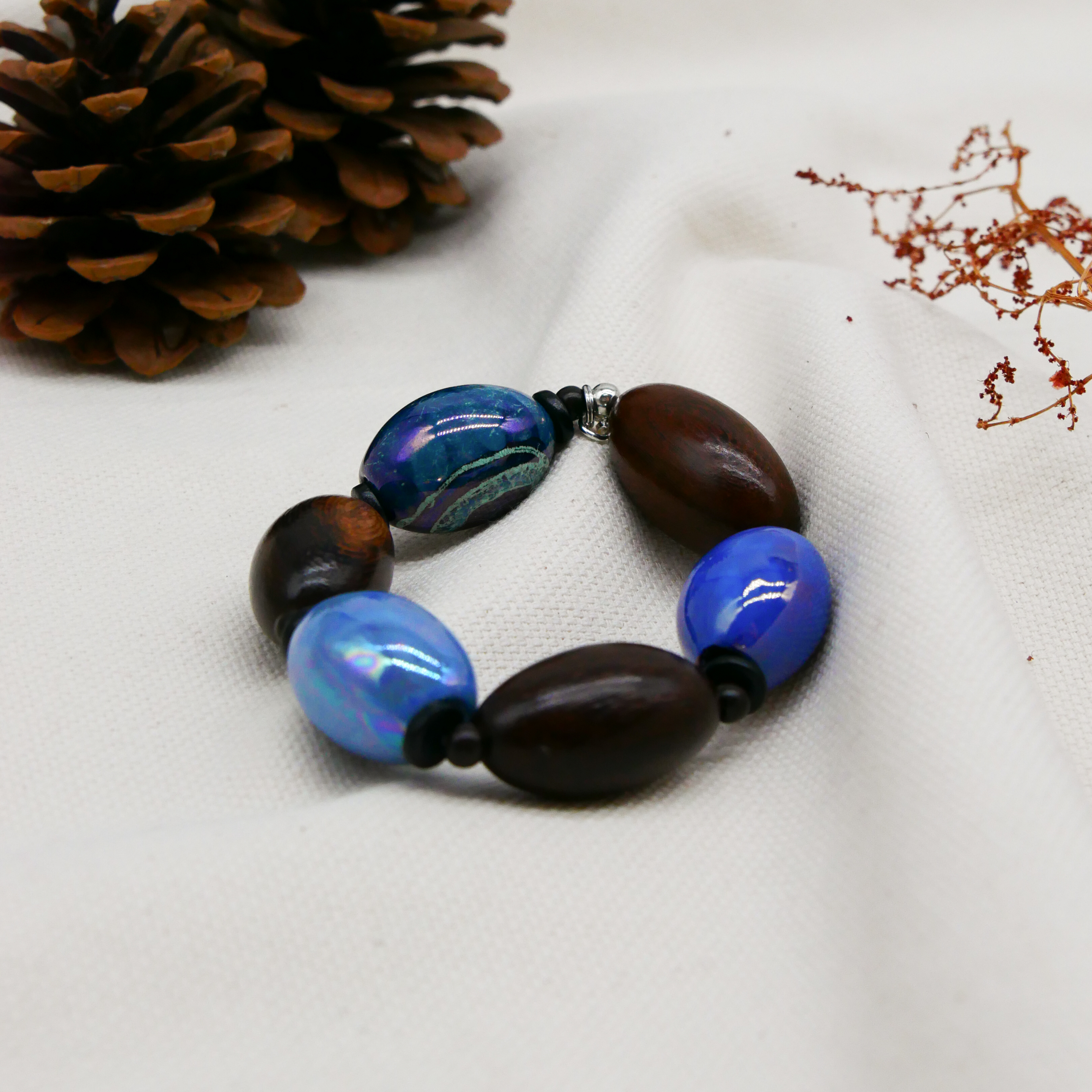 "Woodland" Armband auf Gummi "Olive", Robles Holzoliven und Keramikoliven, braune und blaue Töne "Woodland" Armband auf Gummi "Olive", Robles Holzoliven und Keramikoliven, braune und blaue Töne