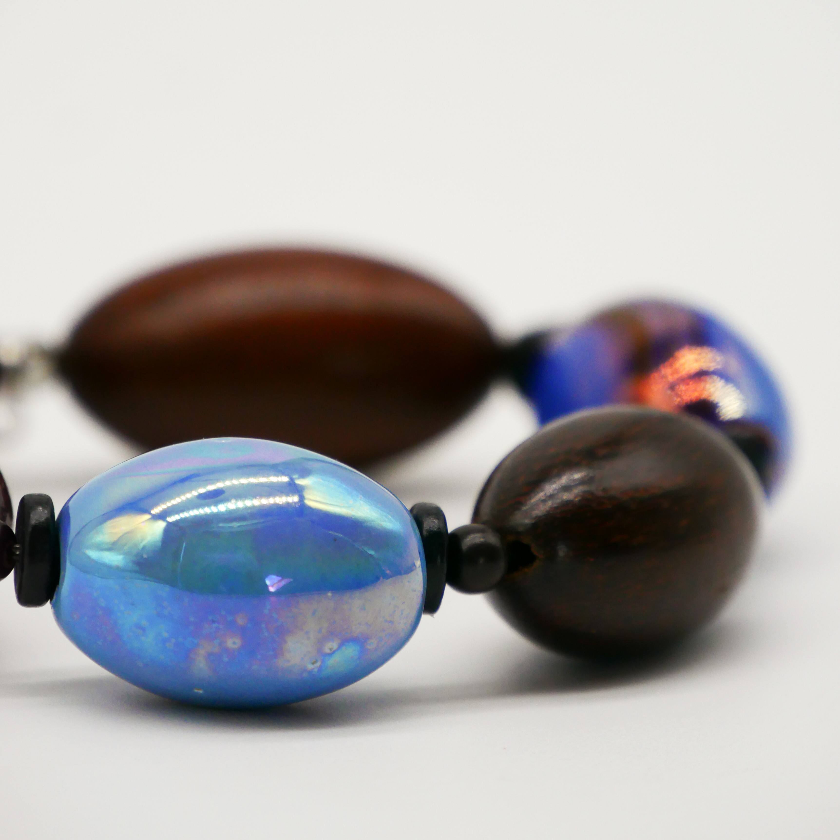"Woodland" Armband auf Gummi "Olive", Robles Holzoliven und Keramikoliven, braune und blaue Töne "Woodland" Armband auf Gummi "Olive", Robles Holzoliven und Keramikoliven, braune und blaue Töne