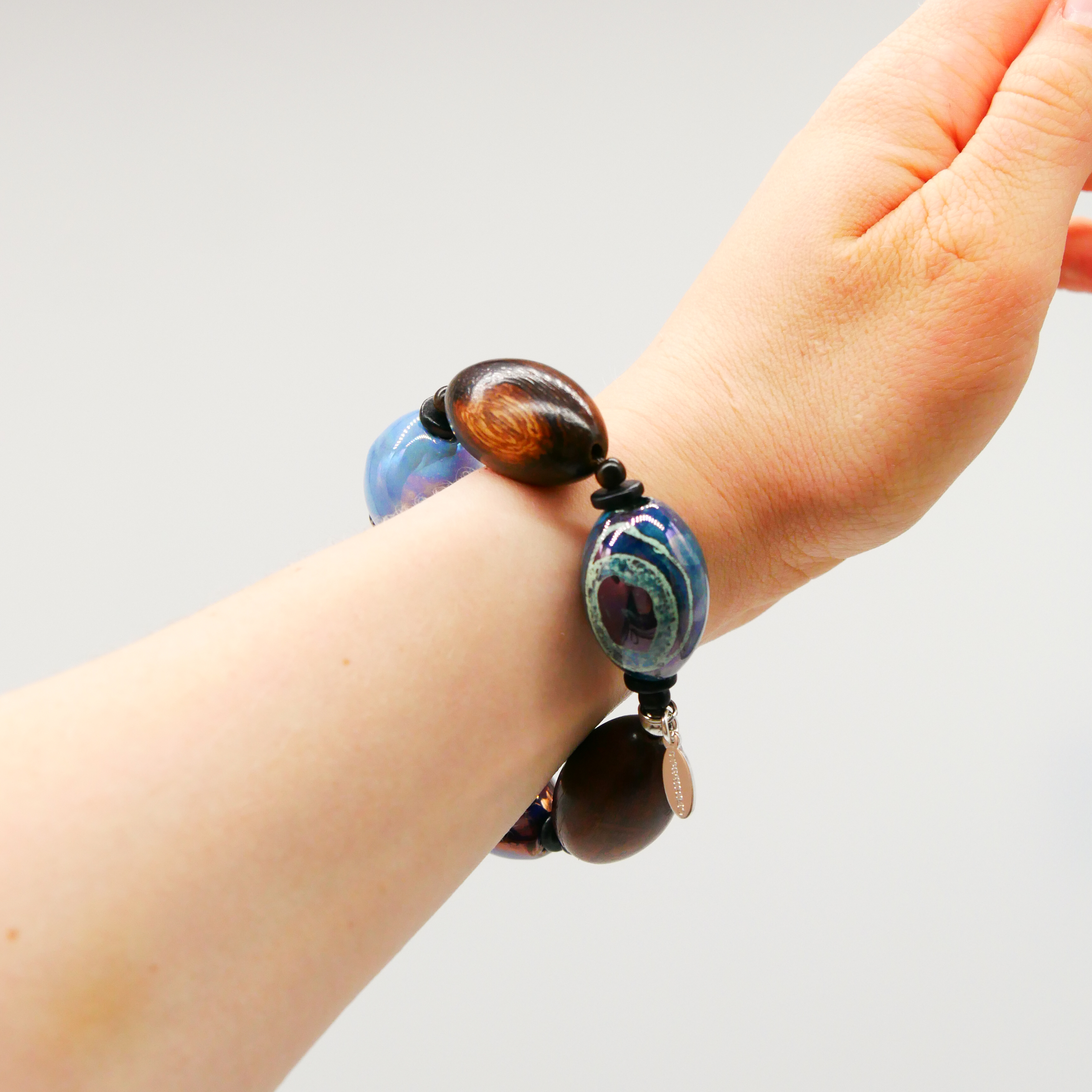 "Woodland" Armband auf Gummi "Olive", Robles Holzoliven und Keramikoliven, braune und blaue Töne "Woodland" Armband auf Gummi "Olive", Robles Holzoliven und Keramikoliven, braune und blaue Töne